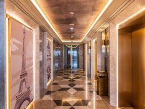 A hallway with a checkered floor, marble walls, and an elevator. - Mercure Tianshui Downtown (Tianshui)