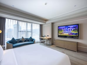 A modern hotel room with a large bed, a desk, a television, and a view of the city through large windows. - Mercure Tianshui Downtown (Tianshui)