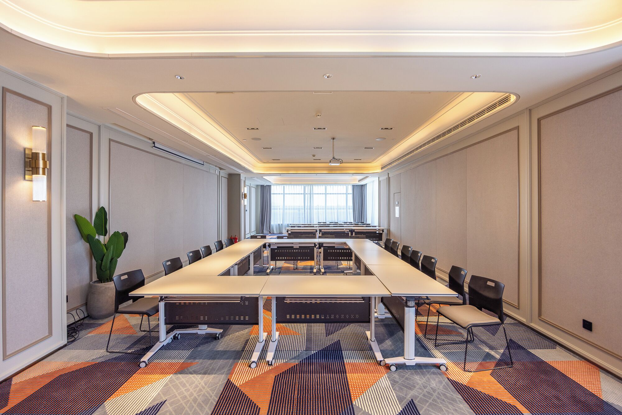 A conference room with a long table, chairs, and a potted plant.