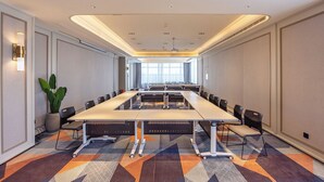 Una sala de conferencias con una mesa larga, sillas y una planta en maceta.