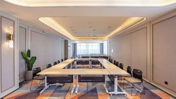 A conference room with a long table, chairs, and a potted plant.