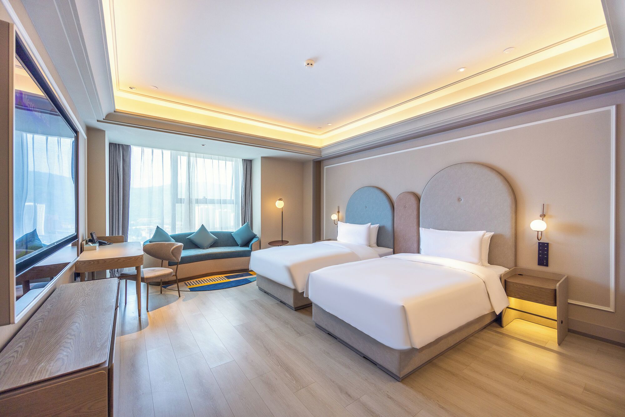 Habitación de hotel con dos camas, un escritorio y una zona de estar con vistas.