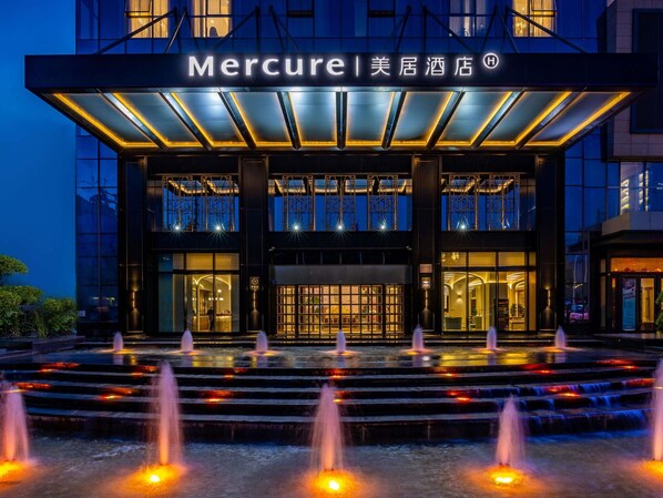 A hotel entrance with a water feature in front, a covered entrance, and a sign above. - Mercure Tianshui Downtown (Tianshui)