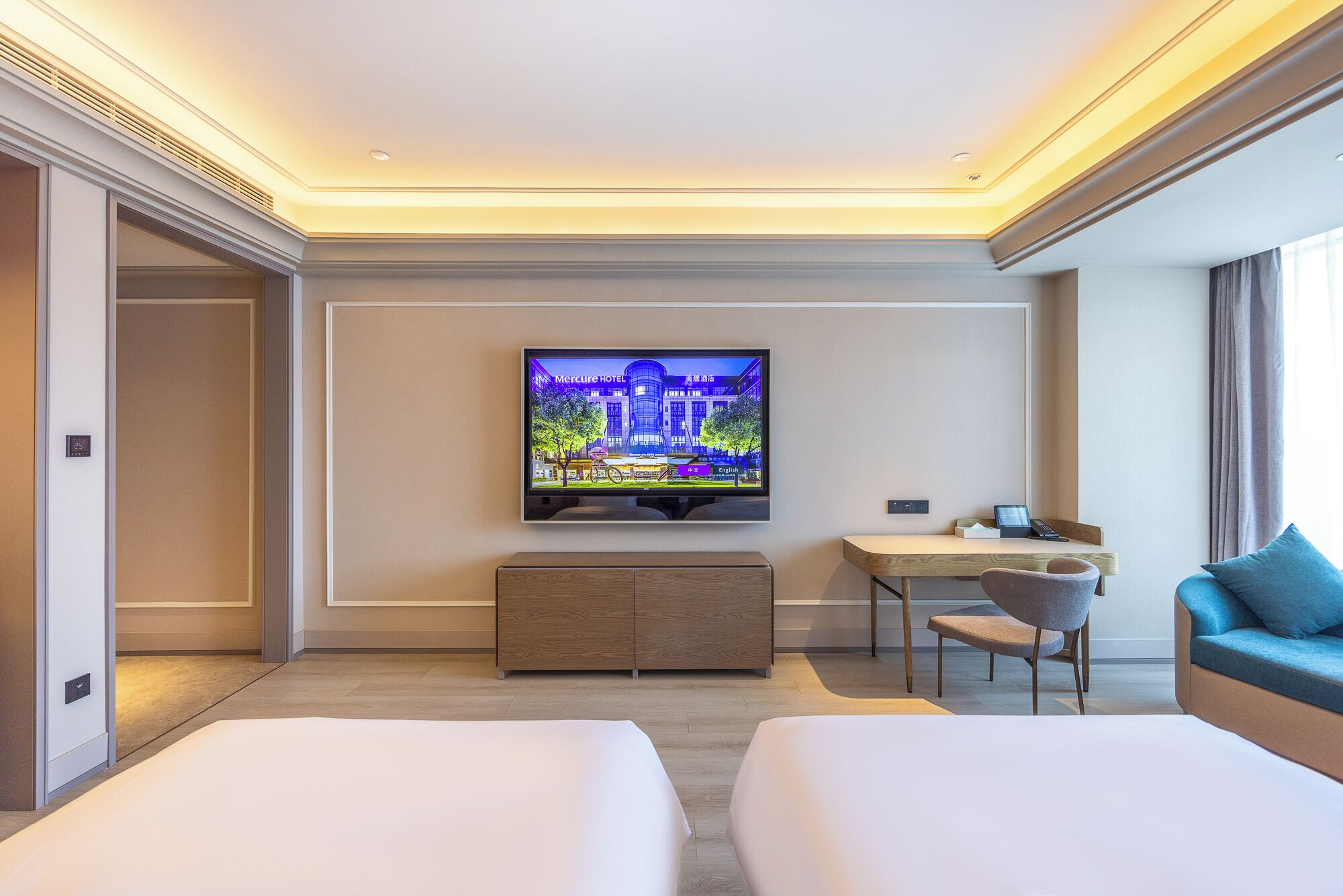 Habitación de hotel con cama, escritorio, silla, televisor y vista a un edificio.