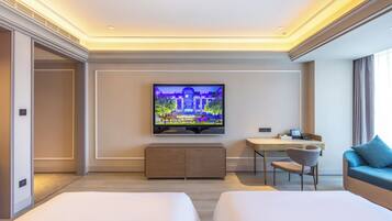 Habitación de hotel con cama, escritorio, silla, televisor y vista a un edificio.