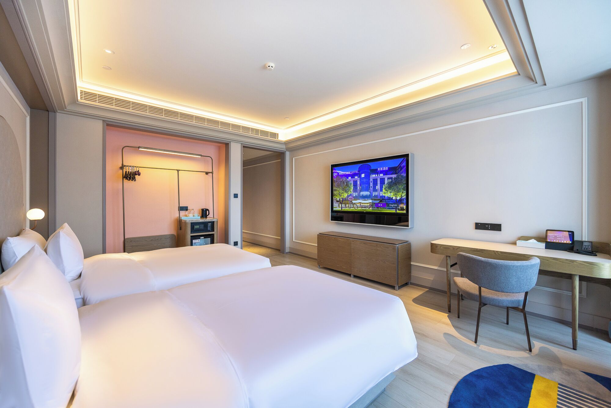 A hotel room with a bed, a desk, a chair, a television, and a bathroom with a mirror and towel rack.