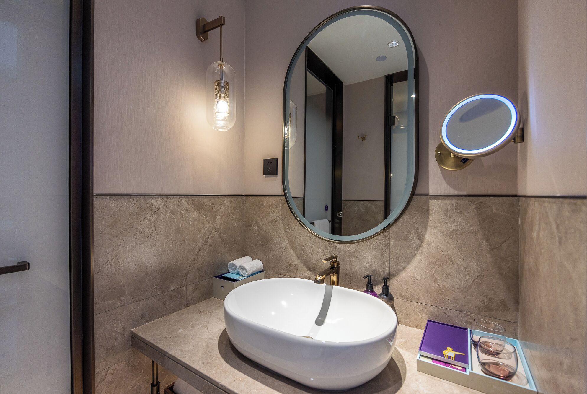 Un baño con un lavabo blanco, un espejo y una lámpara.