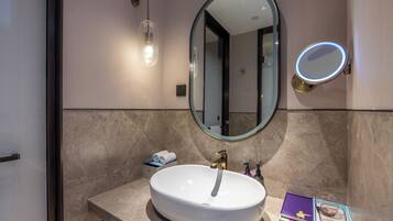 Un baño con un lavabo blanco, un espejo y una lámpara.