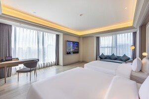 Una habitación de hotel con cama, escritorio, silla, televisor y sofá.