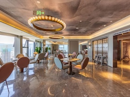Un vestíbulo de hotel moderno con techo alto, pisos de mármol pulido y un accesorio de iluminación circular en el centro.