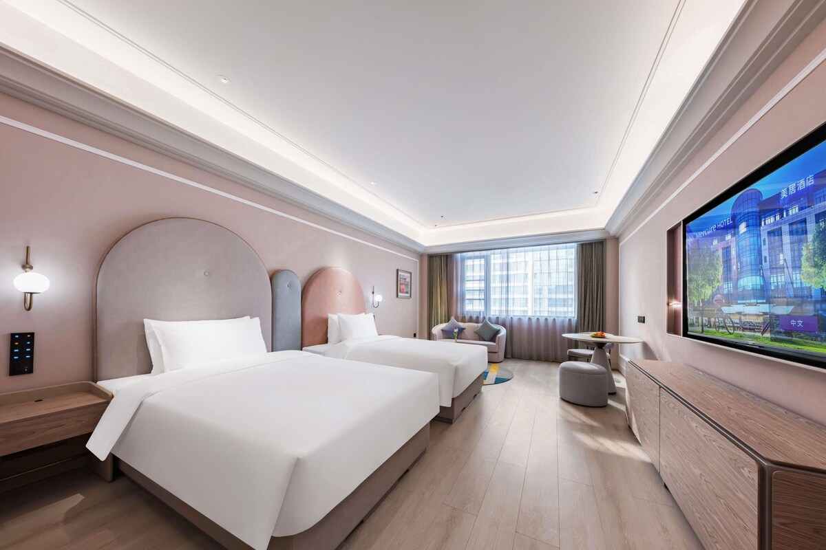 Habitación de hotel con dos camas, televisión, escritorio y sofá.