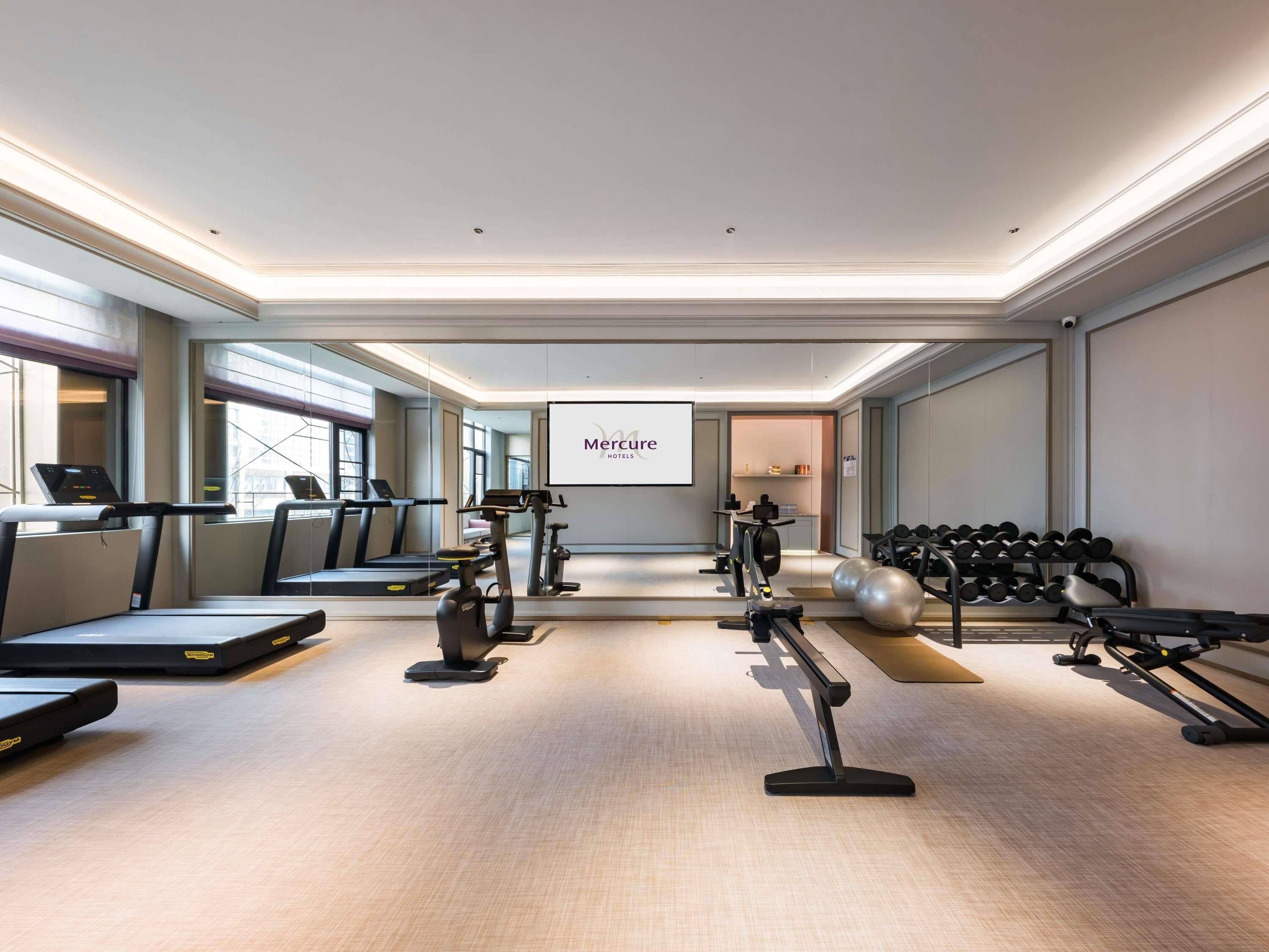 A hotel gym with treadmills, stationary bikes, and dumbbells.