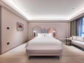 Un dormitorio moderno con una cama grande, mesitas de noche, un sofá y una lámpara de techo.