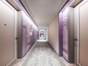 Pasillo de hotel con puertas a ambos lados, alfombra estampada y un largo corredor que lleva a un extremo distante.