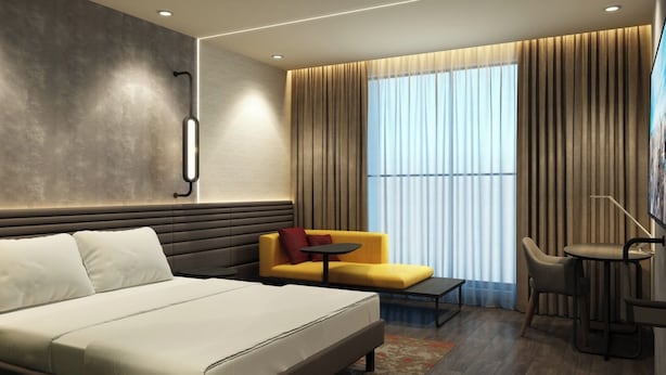 Una habitación de hotel moderna con una cama grande, un sofá, una mesita y una silla.