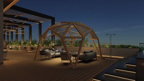 An outdoor deck with wooden flooring, seating arrangements, and a geometric wooden structure.