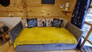 Een houten kamer met een bed, een ronde tafel en een raam met gordijnen.