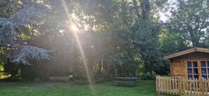 Eine Holzhütte mit Picknicktisch und Bank inmitten eines bewaldeten Gebietes.