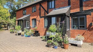 A red brick building with multiple windows and a paved courtyard. - Chess Cottage (Hereford)