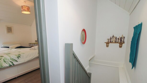 A bedroom with a bed, a nightstand, a lamp, and a wall-mounted shelf with decorative items. - Chess Cottage (Hereford)