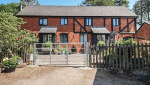 A traditional red brick farmhouse with a gated entrance, a wooden fence, and potted plants. - Chess Cottage (Hereford)