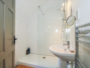 A modern bathroom with a glass shower enclosure, a white sink, and a wooden bath bench. - Chess Cottage (Hereford)