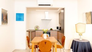 A modern kitchen with a dining area, a small table with a lamp, and artwork on the walls. - Designer Home in Center Town (Lucca)