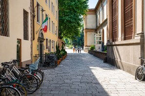 Un carrer empedrat flanquejat per edificis, amb bicicletes aparcades al costat i una bandera.