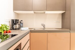 A modern kitchen with a built-in coffee maker, a sink, and a countertop with a plant and tomatoes. - Designer Home in Center Town (Lucca)