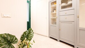 A hallway with a white door, a plant, and a grey cabinet with shelves. - Designer Home in Center Town (Lucca)