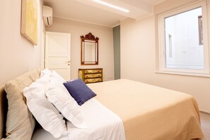 Ein Schlafzimmer mit Bett, Schminktisch, Spiegel und Fenster.