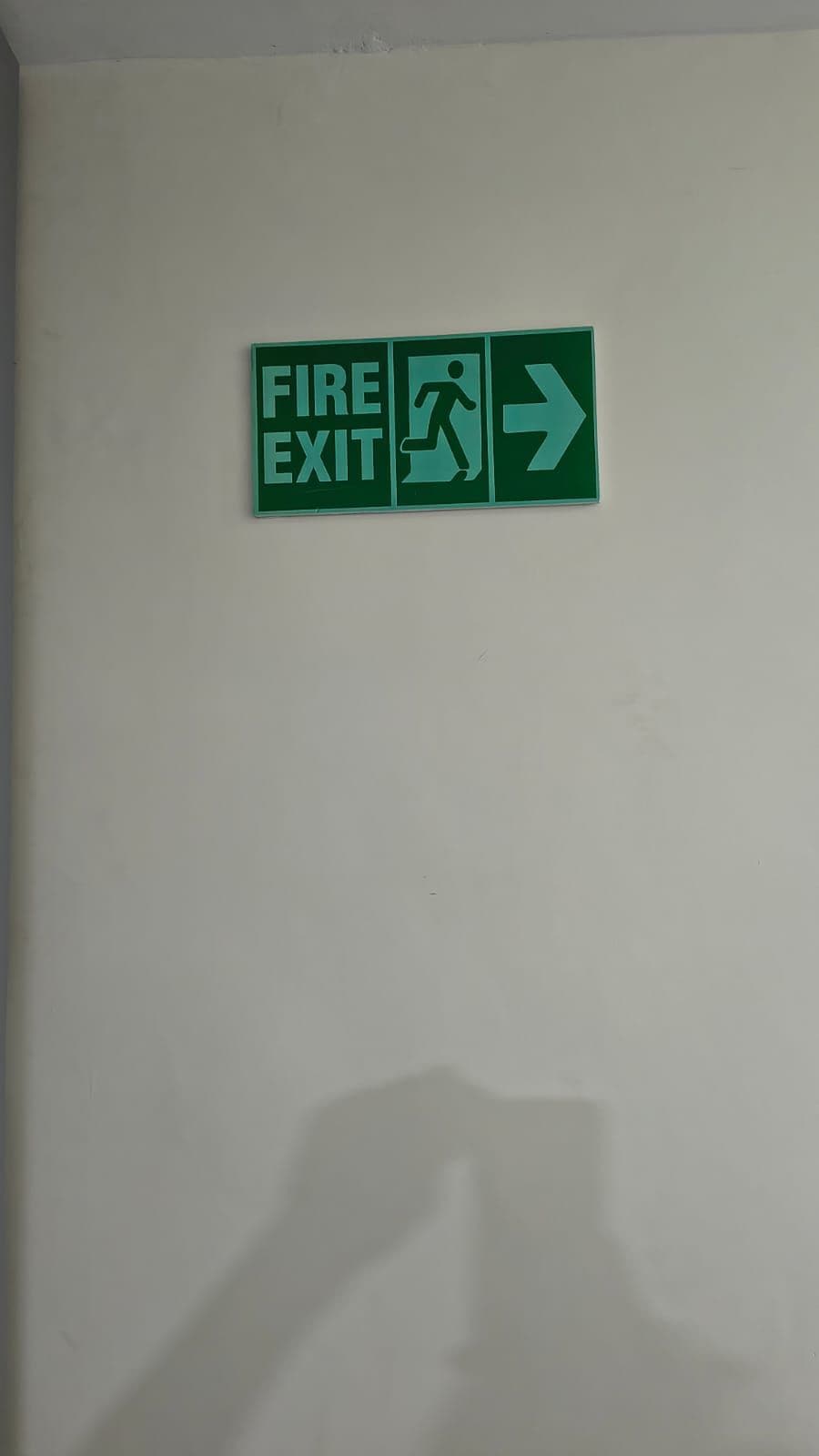 Señal de salida de emergencia con flecha direccional, fijada a la pared.