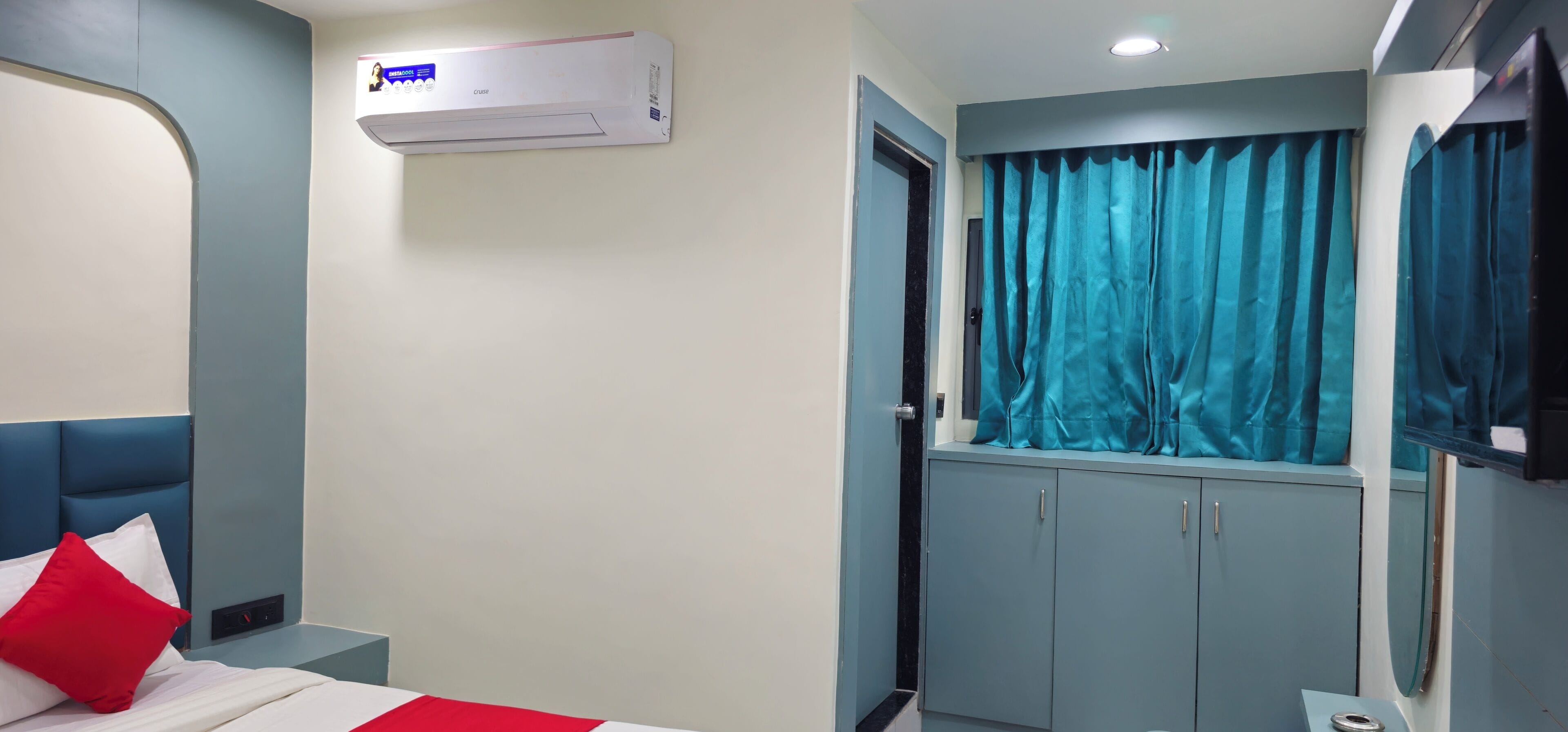 Una habitación de hotel con cama, ventana con cortinas, armario y equipo de aire acondicionado.