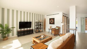 Uma sala de estar moderna com televisão de tela plana, mesa de centro, sofá e estante de livros.