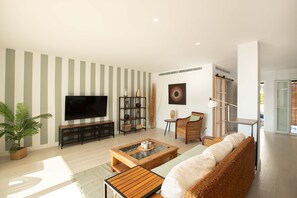 Ein modernes Wohnzimmer mit Fernseher, Couchtisch, Sofa und Bücherregal.