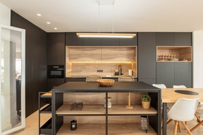 Eine moderne Küche mit Holztischplatte, schwarzen Schränken und einem eingebauten Backofen.