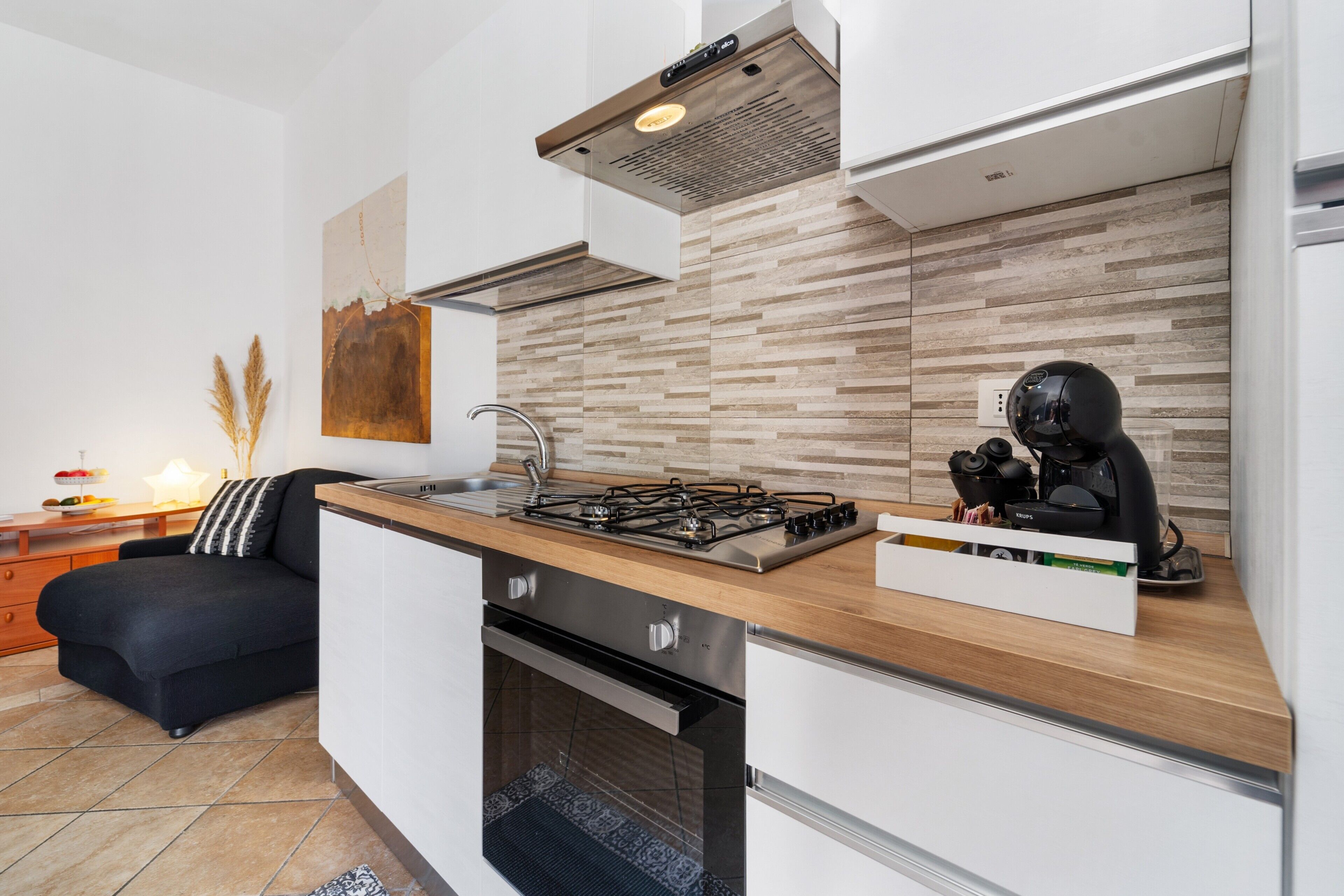 A modern kitchen with a gas stove, oven, and a coffee machine on the counter.