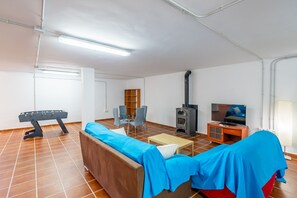 A furnished living room with a sofa, a coffee table, a television, a fireplace, and a foosball table. - Cubo's Amapola House / Private pool / BBQ / Free Wi-Fi (Alhaurin de la Torre)