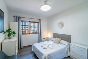 A hotel room with a bed, bedside table, lamp, curtains, window, and a potted plant. - Cubo's Amapola House / Private pool / BBQ / Free Wi-Fi (Alhaurin de la Torre)