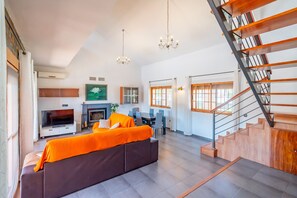 Un salon moderne avec un canapé, un téléviseur, une cheminée et un escalier.