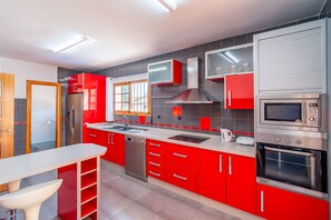 Une cuisine moderne avec des meubles de couleur rouge, des appareils en acier inoxydable et un plan de travail blanc.