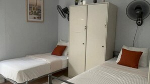 A room with two single beds, a wardrobe, a wall-mounted fan, and a framed picture on the wall. - A haven in the heart of Lisbon—just 4 minutes from the Metro. Double and quadruple rooms. (Lisboa)