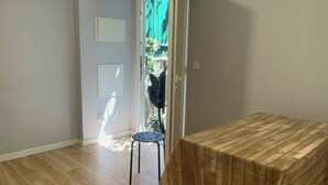 A room with a wooden floor, a table, a chair, and a door leading to a balcony. - A haven in the heart of Lisbon—just 4 minutes from the Metro. Double and quadruple rooms. (Lisboa)
