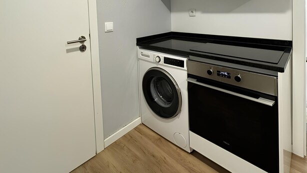 A compact laundry room with a washing machine, dryer, and a countertop. - A haven in the heart of Lisbon—just 4 minutes from the Metro. Double and quadruple rooms. (Lisboa)