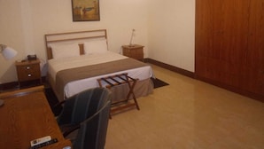 Habitació d'hotel amb un llit, una taula de nit, una l àmpada i un quadre a la paret.