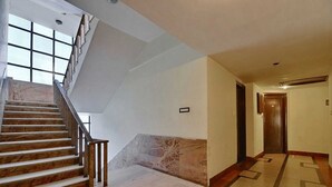Un'elegante hall d'albergo con una scalinata in marmo, un pavimento decorato e una porta in legno in fondo.