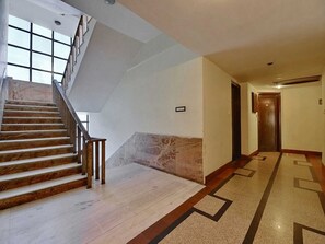 A hotel lobby with a marble staircase, a patterned floor, and a wooden door at the end. - Standard King Room Palette Hotel Jaipur (Jaipur)