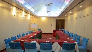 Una sala conferenze con un lungo tavolo, sedie blu e una lavagna.