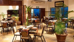 Un ristorante con diversi tavoli e sedie, piante in vaso e vista sull'esterno.