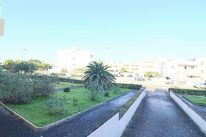 Zona residencial con un sendero, vegetación y edificios al fondo.